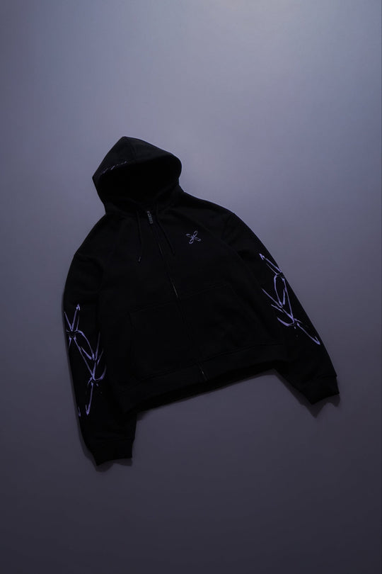 Black zip hoodie with purple designs on a dark purple background